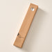 A tall, narrow cardboard box with a circular window display cutout at the top showing two natural white candles inside, photographed on a clean off-white background. The box has printed text near the bottom including the brand name 'Ten Thousand Villages'.