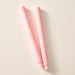 Two ginger pink colored pillar candles with ribbed bases, laying flat on a white background.