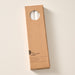 A tall, narrow cardboard box with a circular window display cutout at the top showing two natural white candles inside, photographed on a clean off-white background. The box has printed text near the bottom including the brand name 'Ten Thousand Villages'.