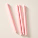 Four ginger colored taper candles laying flat on a light beige background.